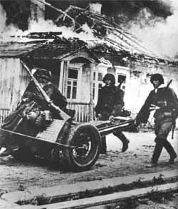 Группа бойцов "Лейбштандарта" бредет мимо горящих домов в ходе отступления из-под Курска