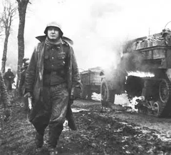 Кадр из немецкого пропагандистского фильма: солдат 6-й армии СС идет митмо горящей американской техники.
