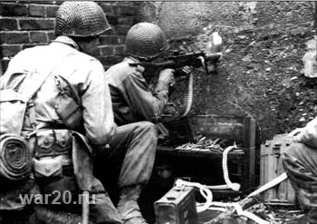 Американские пулеметчики ведут стрельбу по немецким солдатам через пролом в стене. Германия, октябрь 1944 года.